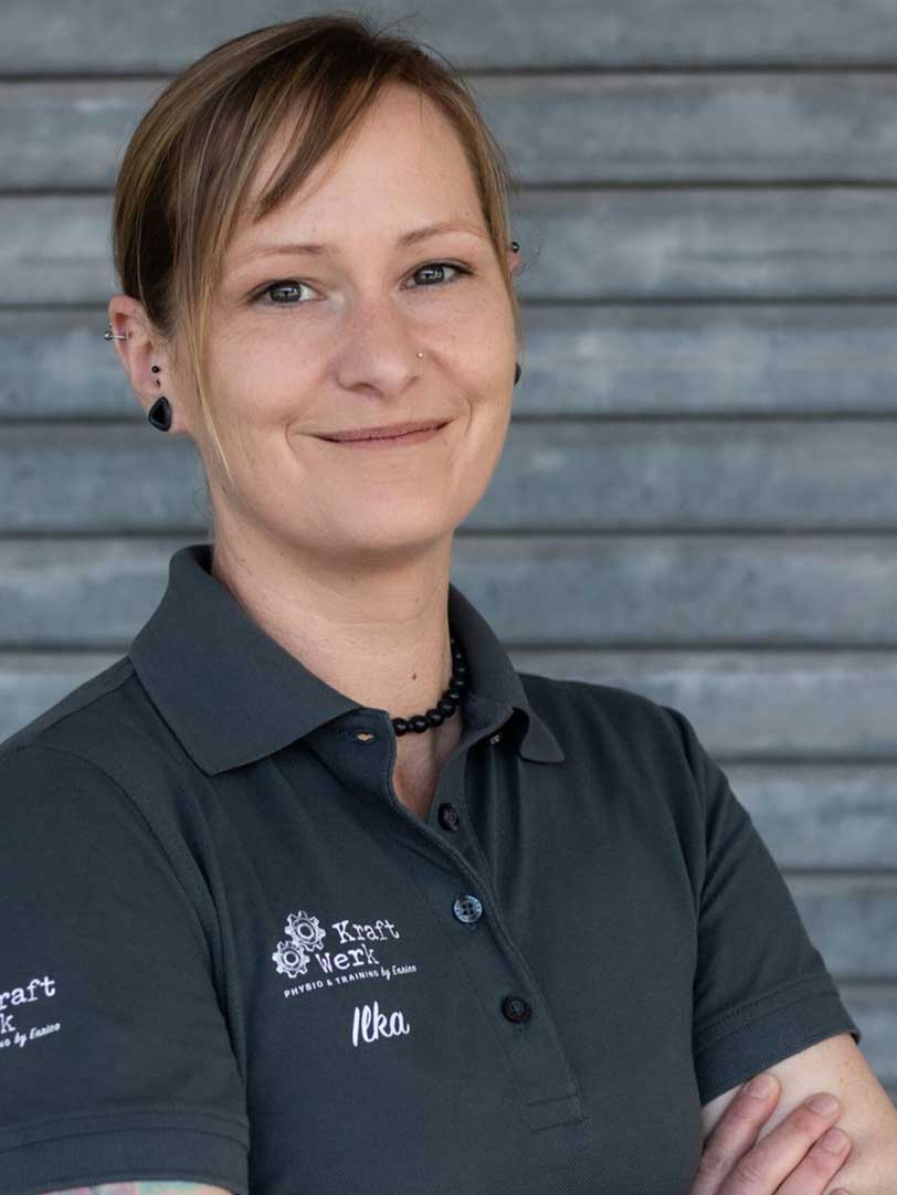 Eine lächelnde Frau mit kurzen blonden Haaren trägt ein graues Polohemd.